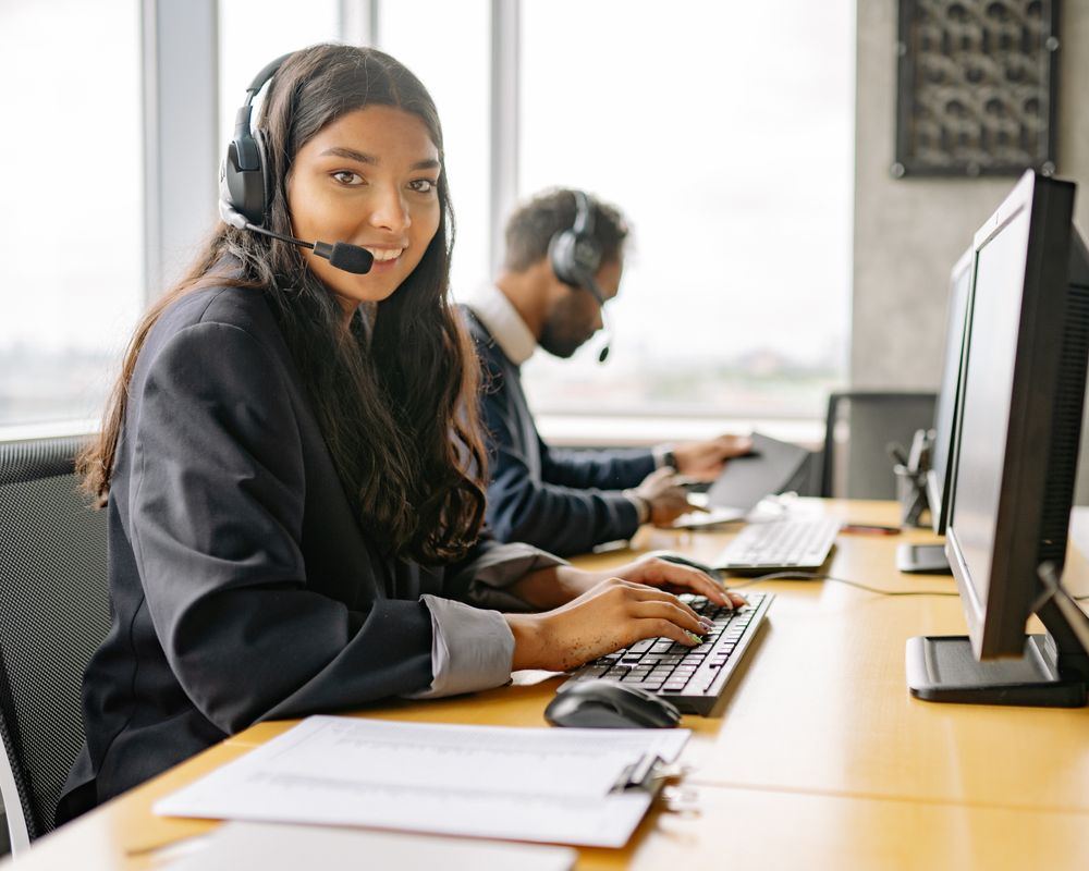 Smiling support agent wearing a headset at her desk